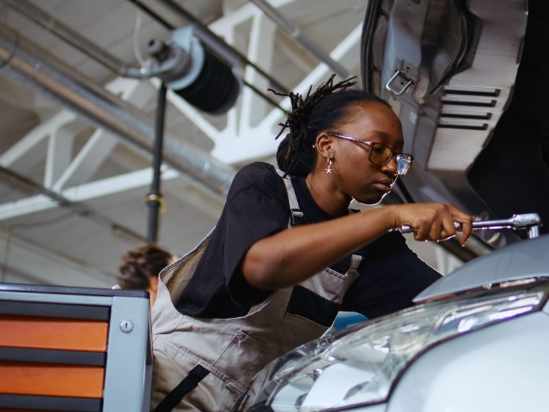 Licensed repairman in repair shop using torque wrench to tighten screws after checking car parameters during maintenance. Expert using professional tool in garage to mend vehicle, close up shot